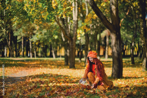 Redhaired girl in a hat collects autumn leaves in an aquarium. Concept