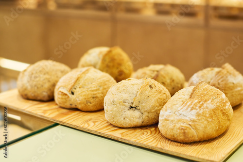 Several loaves of fresh wheat bread on wooden board or tray on display or counter desk prepared for selling to customers of bakery shop