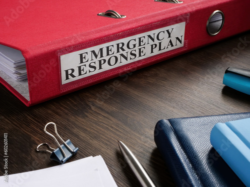 Red folder with Emergency response plan on the desk.