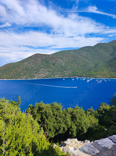 This stunning aerial view showcases the vivid blue Mediterranean Sea with boats  framed by mountains  and enveloped in lush trees. Embrace nature s captivating harmony. The essence of Greek tourism.