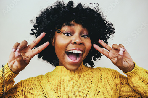happy black woman smiling with open mouth and fingers in victory sign