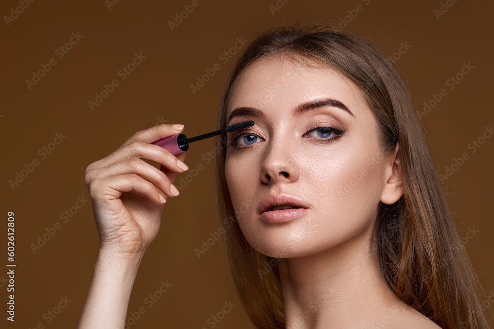 Obraz premium young woman applying black mascara on long thick eyelashes