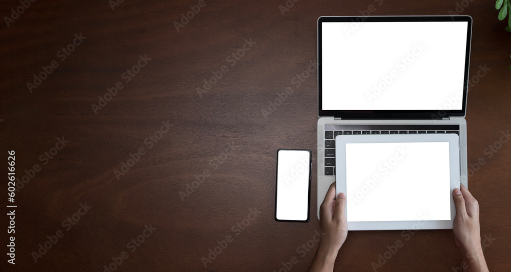 Top view of businesswoman sitting at white desk and uses smartphone on table are laptop and digital tablet with blank screen.Girl using gadget. Top view of businesswoman sitting at white desk and uses smartphone on table are laptop and digital tablet with blank screen.Girl using gadget.