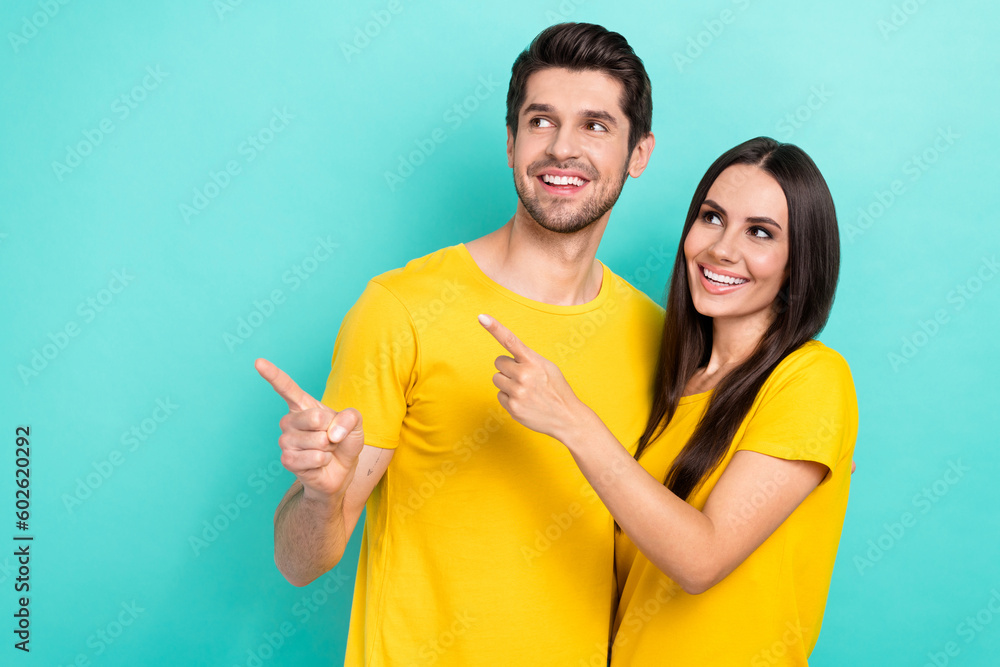 Photo of young lovely couple dating feelings together wear yellow stylish t-shirt directing finger empty space isolated on cyan color background - obrazy, fototapety, plakaty 