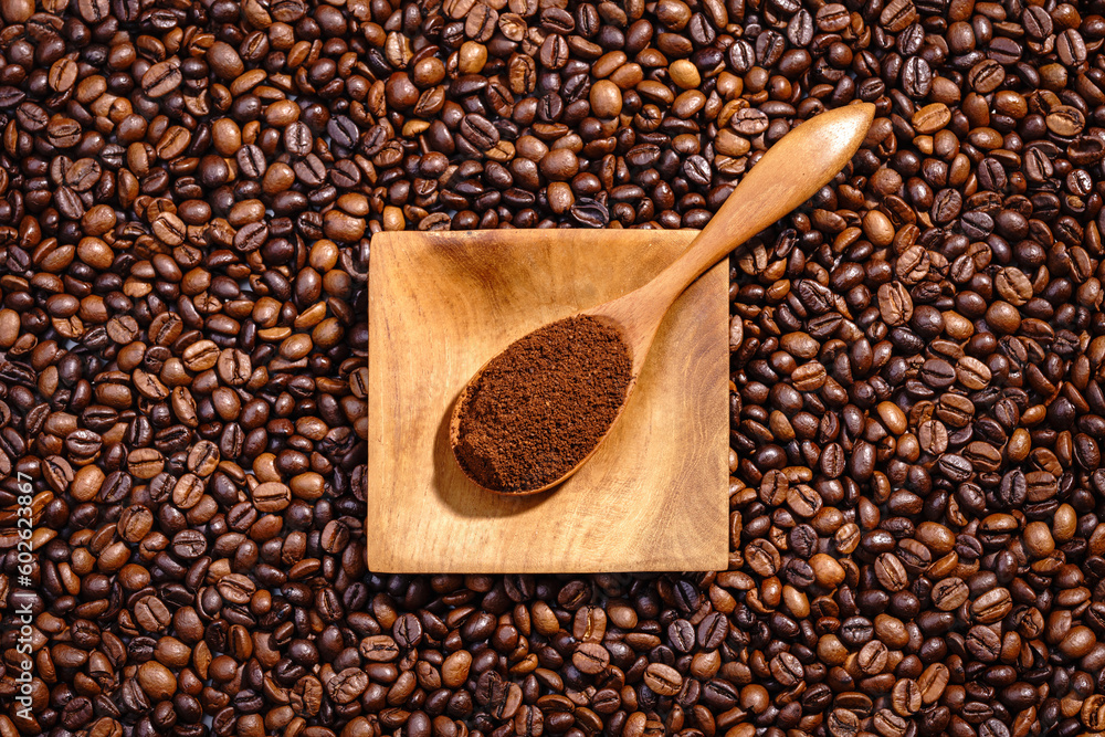 Fototapeta premium Palone ziarna kawy z drewnianym podstawkiem wypełnionym kawą