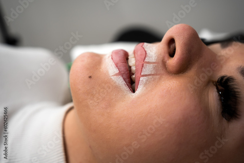 Makeup artist applay permanent makeup procedure. Lips makeup in the cosmetologist's salon. photo