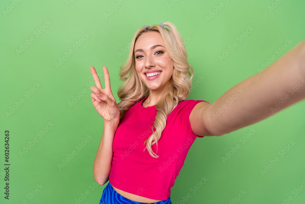 Photo of cute funny woman wear pink top tacking selfie showing v-sign isolated green color background Photo of cute funny woman wear pink top tacking selfie showing v-sign isolated green color background