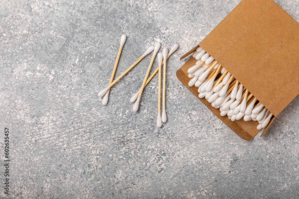 Cotton buds in eco kraft packaging on a textured background. Cotton swab on a white background. Sticks for hygiene of the nose and ears. Bamboo cotton buds. Eco friendly.Place for text.Space for copy. Cotton buds in eco kraft packaging on a textured background. Cotton swab on a white background. Sticks for hygiene of the nose and ears. Bamboo cotton buds. Eco friendly.Place for text.Space for copy.