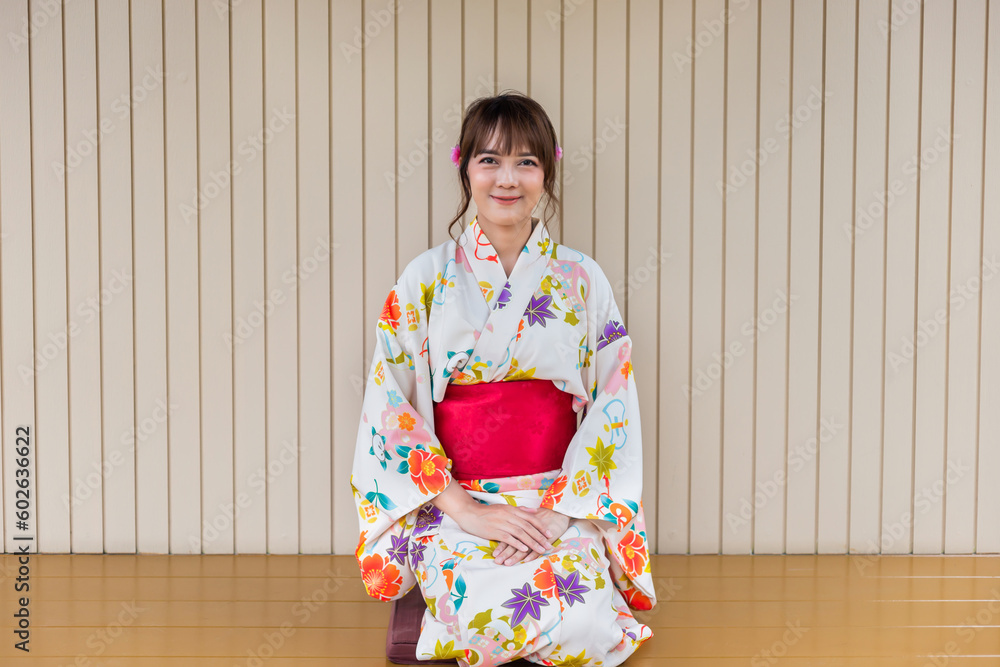 Young woman wearing traditional kimono sitting in Japanese style house with tea set with garden background Young woman wearing traditional kimono sitting in Japanese style house with tea set with garden background