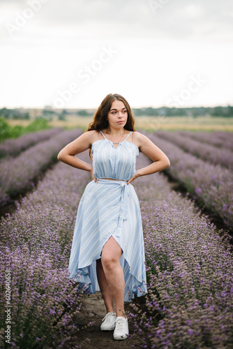 Fototapeta Naklejka Na Ścianę i Meble -  Girl standing in lavender flowers field. Woman walk on the lavender field. Enjoy the floral glade, summer nature. Natural cosmetics concept. Female on background of lavender. France, Provence. Closeup