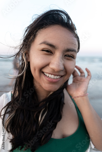 Portrait of a young Hispanic woman smiling in front of the sea at the beach
