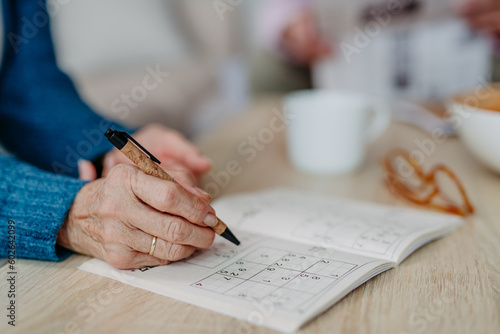Close up of senior woman doing crossword puzzle. photo