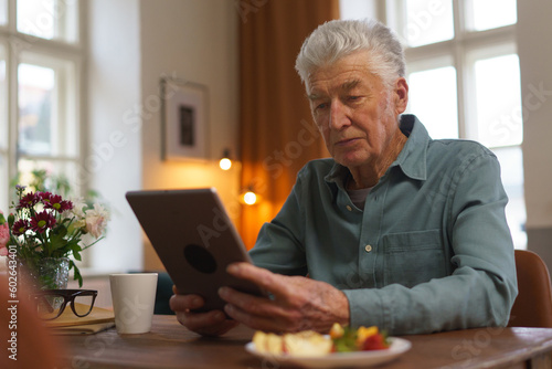 Senior man reading something in digital tablet.
