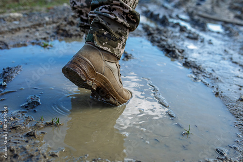 Armed Forces of Ukraine. Ukrainian soldier. Brown military boots on mud and puddle. photo