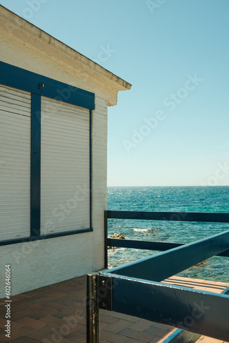 Front view of seashore with white house, turquoise ocean water and horizon © LS Visuals