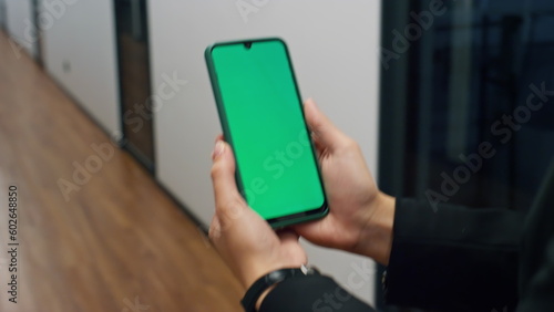 Closeup hands holding smartphone with chroma key screen. Manager walking office