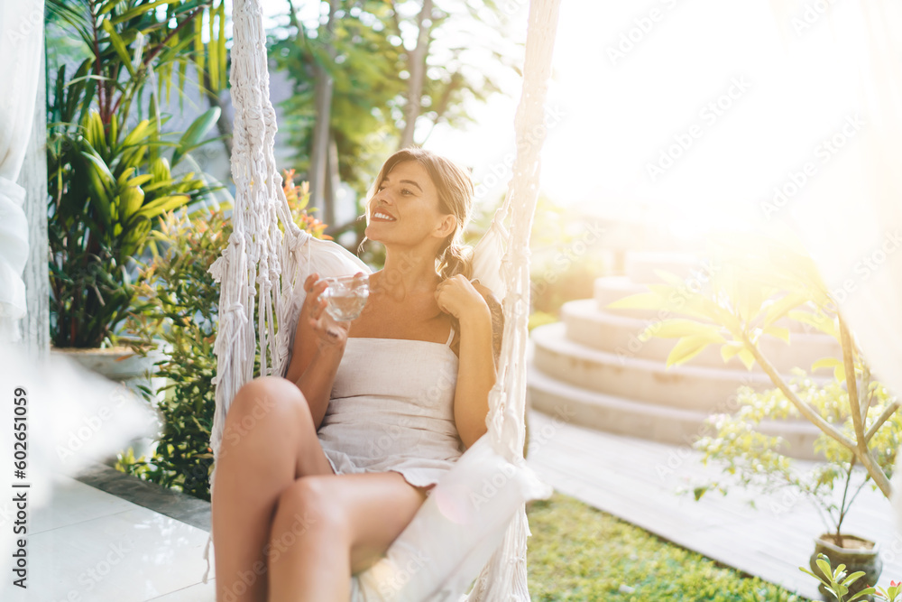 Woman resting on hammock chair on terrace of hotel Woman resting on hammock chair on terrace of hotel