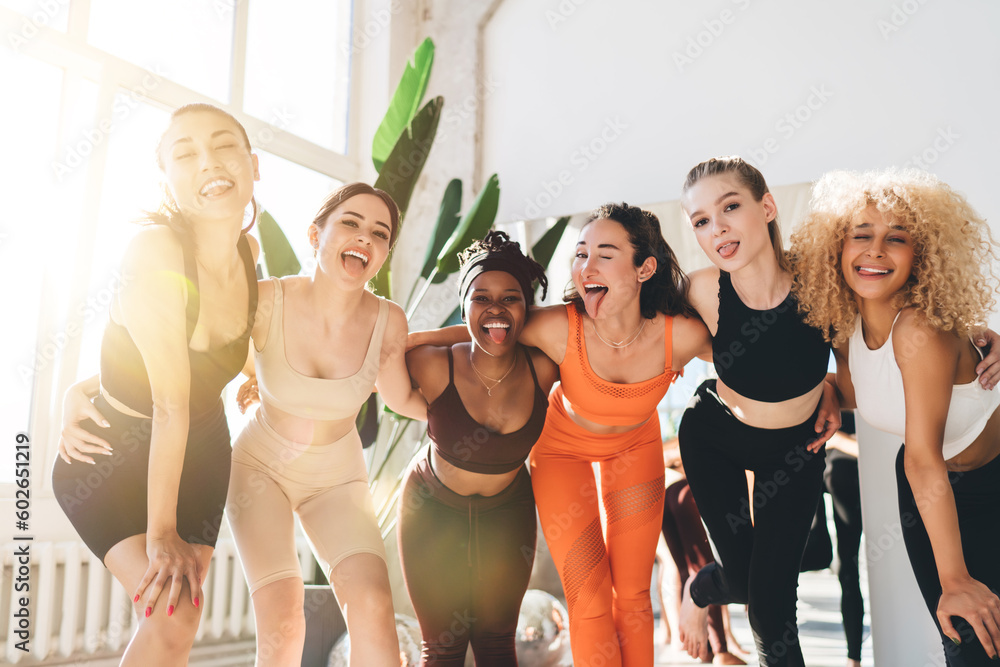Fototapeta premium Group of multiracial sportswomen posing for camera in gym
