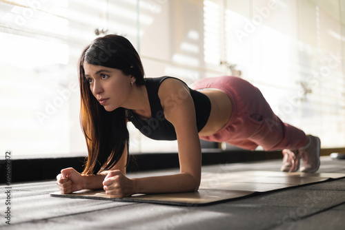 physical activity, performing a pushup to strengthen body a slim woman with long latin hair wears sportswear, healthy lifestyle, training at home