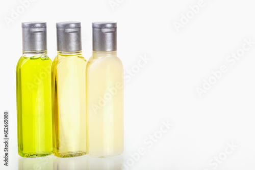 Travel cosmetic set of three small bottles of cosmetics on white background on white background. Shampoo, shower gel, body lotion. Travel, trips, hotels. Cosmetics mockup, advertising