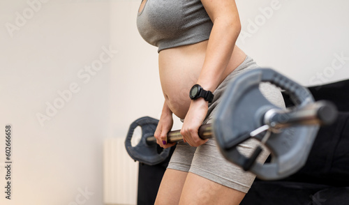 Canvastavla An unrecognizable pregnant woman is working her back by rowing with a bar in her living room