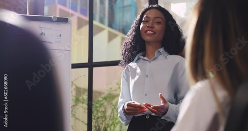 Confident young businesswoman sharing ideas with colleagues during team meeting.