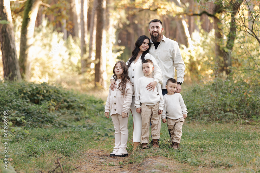 Portrait of big family outdoors. Young Stylish bearded dad with little son on shoulder, beautiful brunette mom, child boy and daughter in autumn park, smiling and looking at camera. Happy family day Portrait of big family outdoors. Young Stylish bearded dad with little son on shoulder, beautiful brunette mom, child boy and daughter in autumn park, smiling and looking at camera. Happy family day