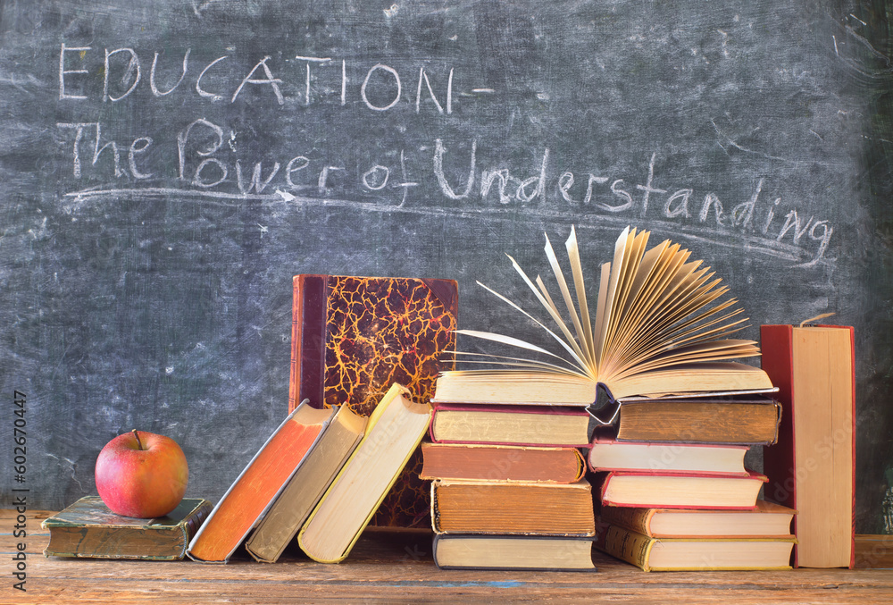 Stack of hardback books with slogan in front of a blackboard.Learning,education,reading,back to school concept. - obrazy, fototapety, plakaty 