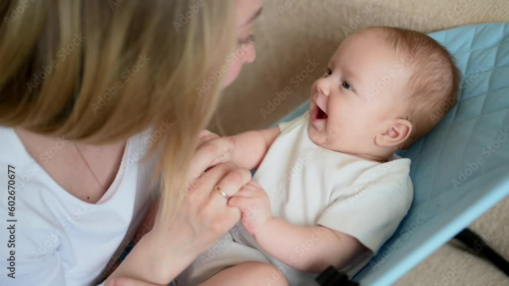 A happy child lies in a children's deck chair,smiles and is happy to see mom,mom talks to the baby. Childhood,motherhood A happy child lies in a children's deck chair,smiles and is happy to see mom,mom talks to the baby. Childhood,motherhood