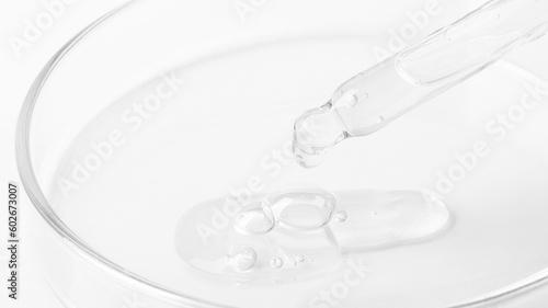 Transparent gel flowing from a pipette into a Petri dish. On a white background. Close-up.