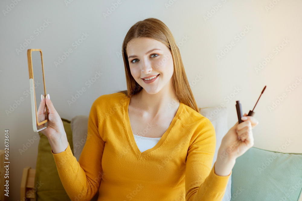 Young Woman Posing Holding Mascara And Mirror Making Makeup Indoors Young Woman Posing Holding Mascara And Mirror Making Makeup Indoors