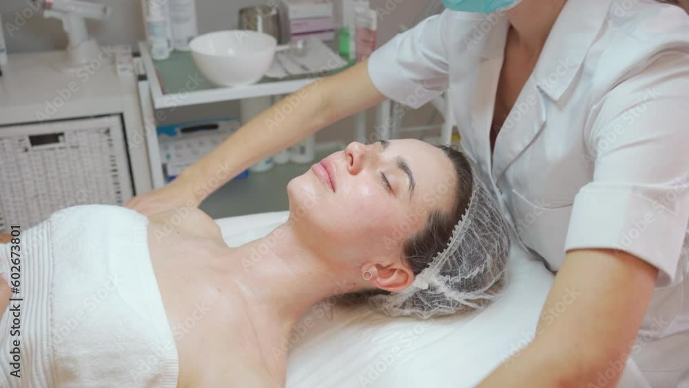 Massage therapist massaging head, shoulders and neck to woman in cosmetology cabinet. Beautician making skincare rejuvenating procedure. Spa treatment and massage in beauty salon. Massage therapist massaging head, shoulders and neck to woman in cosmetology cabinet. Beautician making skincare rejuvenating procedure. Spa treatment and massage in beauty salon.