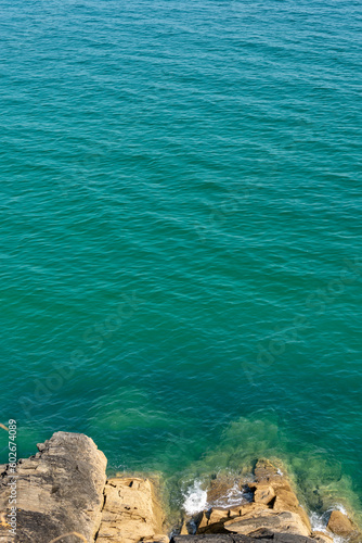 Looking down to rocks and blue pristine sea. Ocean background with copy space