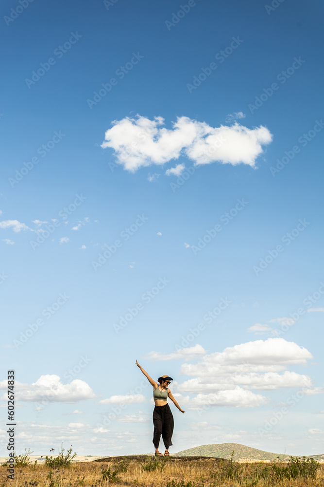 red-haired woman with outstretched arms in a meadow with white clouds and blue sky in the background red-haired woman with outstretched arms in a meadow with white clouds and blue sky in the background