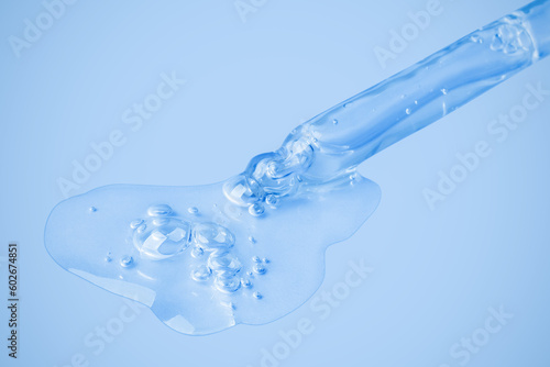 Transparent cosmetic gel flows from an eyedropper directly onto the background in a large blob with bubbles. On a blue background. Hyaluronic acid, toner, toner, gel, cream. Cosmetics. © Marina Red