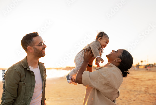 Family's beachside evening. Parents enjoying time with their little son, having fun on the beach, playing and laughing