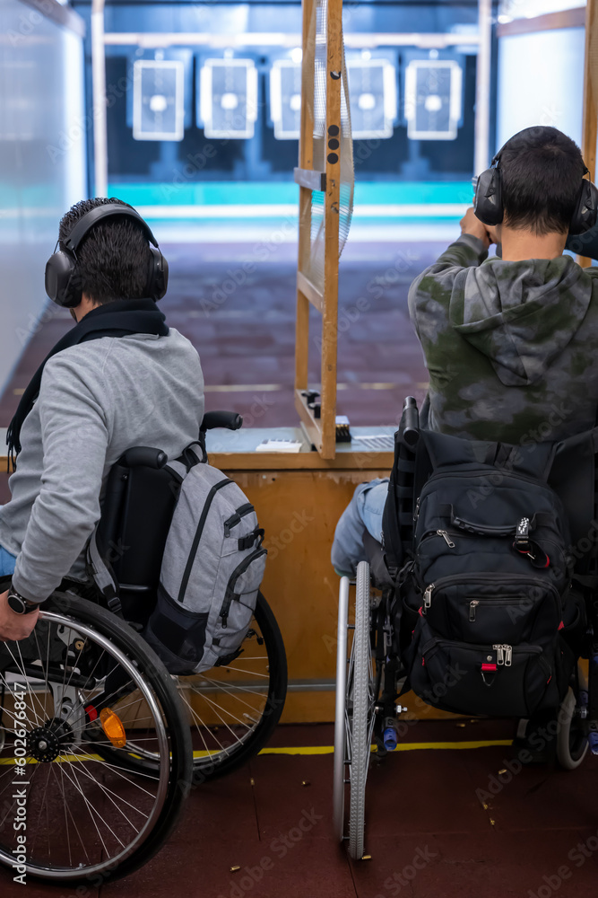 Obraz premium Two Men in Wheelchair Shooting with a Gun on Shooting Range with Target in Switzerland.