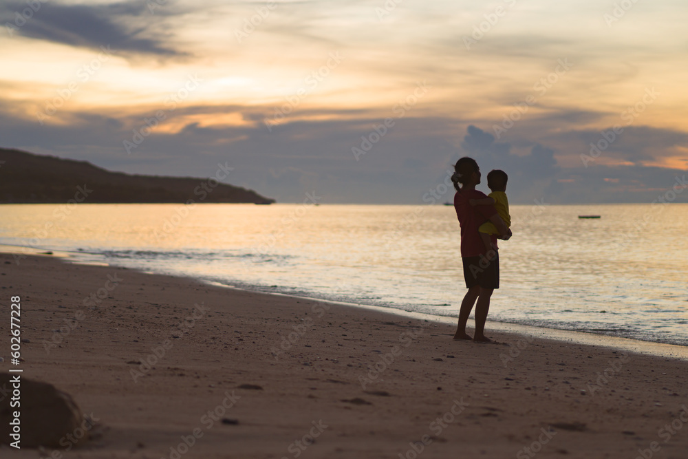 mother holding child on the beach at sunset