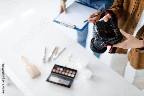 Object photography concept. Male photographer taking photo of cosmetic products, working in team with assistant