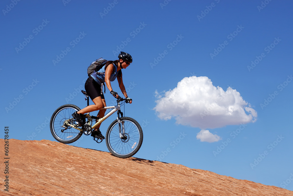 Woman mountain biking on slick rock in Moab, Utah Woman mountain biking on slick rock in Moab, Utah