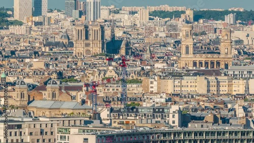 Aerial panorama above houses rooftops in a Paris timelapse. Evening view of Notre Dame de Paris and Saint-Sulpice bebore sunset. Cranes on a construction site photo