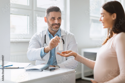 Pregnancy wellness. Young pregnant woman visiting male doctor, therapist giving vitamins or supplements