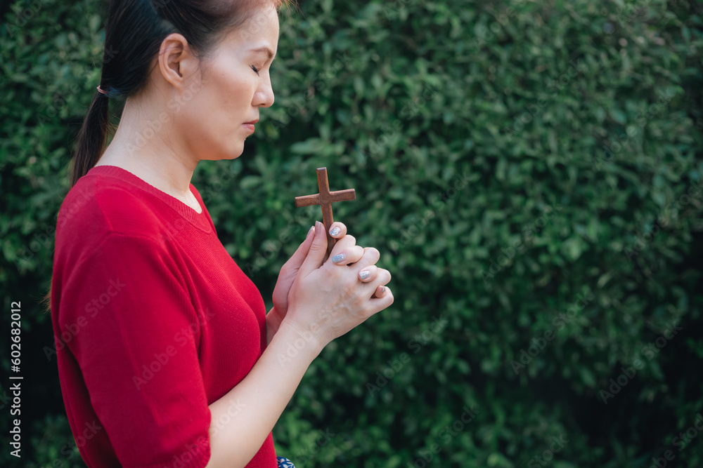 Asian woman praying with wood cross and believe in God Asian woman praying with wood cross and believe in God