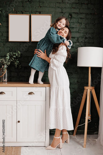 Mother's day. Sensitive young mom embraces her little adorable daughter at home. Trust, support and love between mommy and child. Loving family enjoy tender sweet moments and tight hugs. Children day