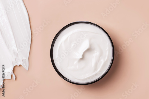 Black can of white cosmetic cream on a beige background. Smeared white cosmetic cream on the background.