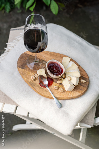 Glass of red wine with camembert on a chair in the garden.