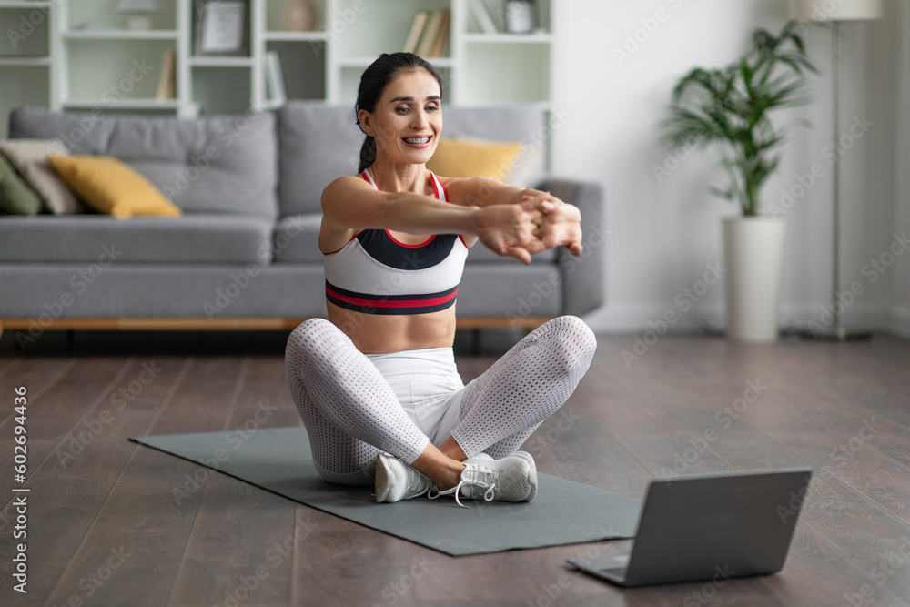 Fototapeta premium Cheerful excited young woman stretching hands at home