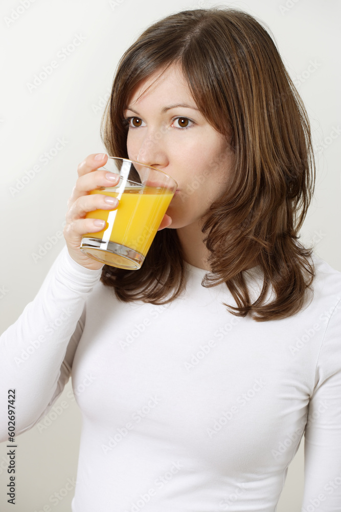 Photograph of a beautiful brunette drinking a glass of orange juice. Photograph of a beautiful brunette drinking a glass of orange juice.