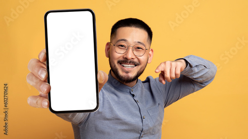 Mobile Ad. Smiling Young Asian Man Pointing At Blank Smartphone In Hand
