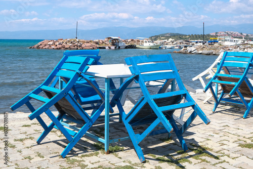 Empty blue white wooden chairs and table near sea. Sea sky travel table chair background. 